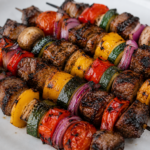 Juicy grilled beef shish kabobs with bell peppers, red onions, mushrooms, zucchini, and tomatoes on skewers fresh from the grill.