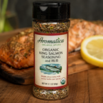 Aromatica Organic Spices Organic King Salmon Seasoning & Rub displayed in a spice jar with grilled salmon and fresh lemon in the background.