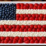Patriotic Fourth of July salad arranged like the American flag with blueberries, strawberries, and feta cheese on a serving platter.