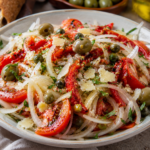 Authentic Spanish Sweet Onion Salad with sweet onions, tomatoes, roasted red peppers, olives, capers, Manchego cheese, and fresh herbs served as a traditional tapas appetizer.